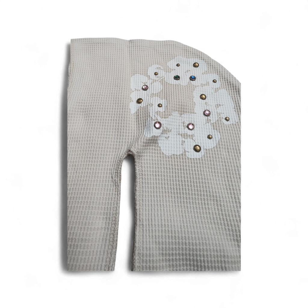 Oatmeal textured Denim Tears with a decorative patch on a white background